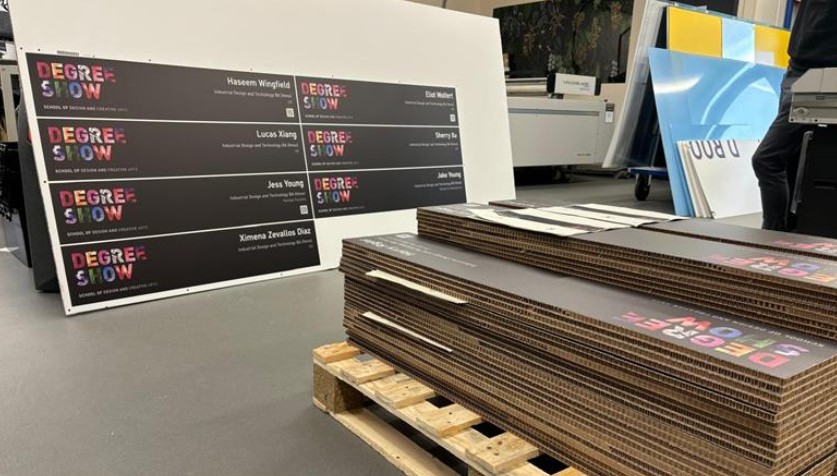 die cut signage piled on a pallet, with an uncut full sheet in the background